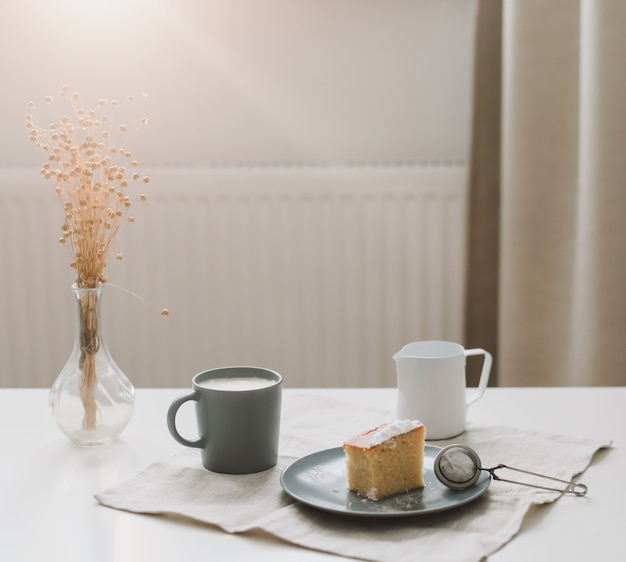 Pedazo de tarta casera fresca con taza de capuchino sobre una mesa