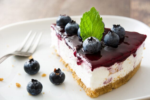 Pedazo de tarta de queso de arándanos en mesa de madera