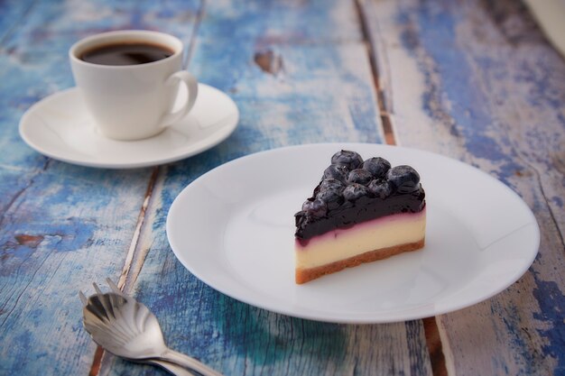 Pedazo de tarta de queso de arándanos en la placa blanca sobre madera