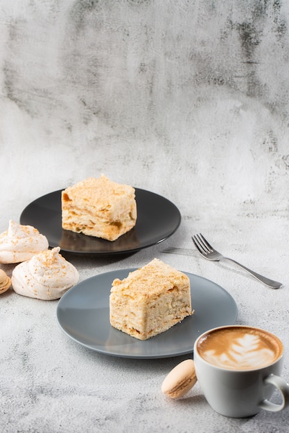 Pedazo de torta Napoleón en la placa azul en el fondo de mármol, visión ascendente cercana. Postre tradicional de milhojas con hojaldre y crema pastelera, copie el espacio. Foto vertical. Foto del menú de panadería.