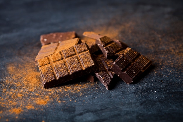 Pedazos de la barra de chocolate montón con polvo de canela.