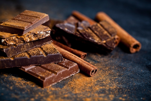 Pedazos de las barras de chocolate con polvo de canela y palos.