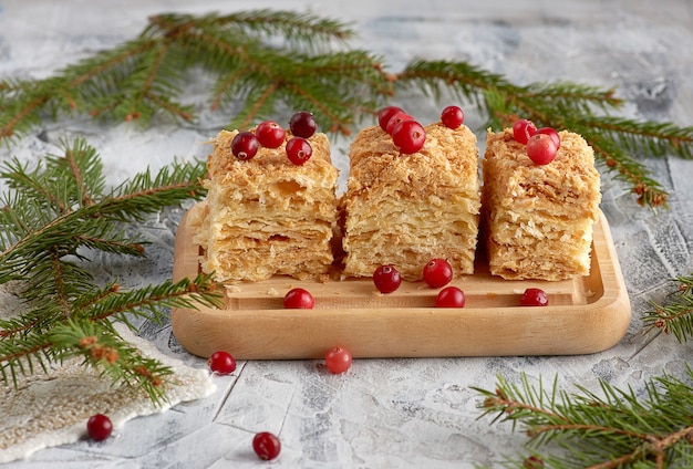 Pedazos de capa de pastel horneado Napoleón con crema de mantequilla sobre una tabla de madera