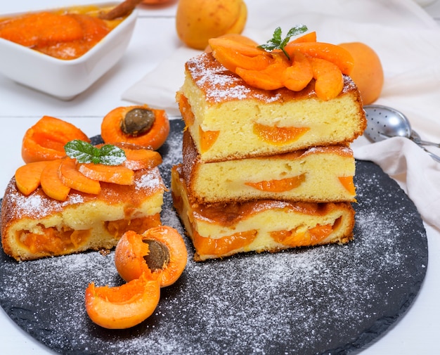 Pedazos cuadrados de pastel de albaricoque en una placa de grafito negro