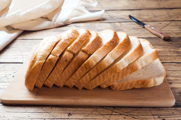 Foto pedazos de pan blanco para tostadas en una mesa de madera.