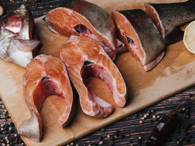 Pedazos de pescado rojo en el tablero sobre la mesa. Primer plano de trucha en rodajas