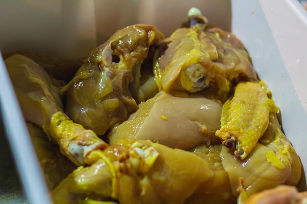 Foto pedazos de pollo sin cocinar en un cubo en la cocina listos para preparar el almuerzo