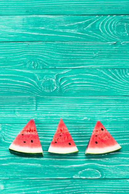 Foto pedazos rojos de sandía fresca en fondo verde