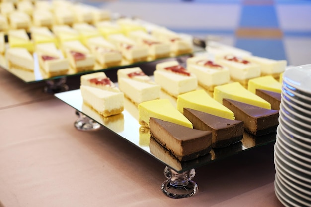 Pedazos de tartas de queso en una bandeja espejada en la mesa de buffet