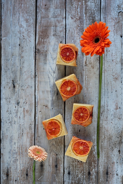 Pedazos de torta de la naranja de sangre y de flor roja en fondo de madera