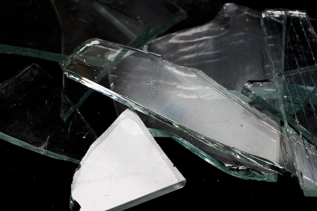 Pedazos de vidrio roto sobre un fondo negro. Foto de alta calidad