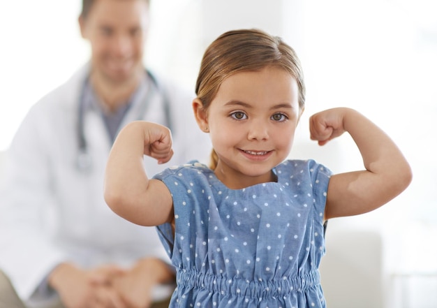 Foto pediatra criança e braço com flexão para o crescimento corajoso e forte com felicidade para o tratamento doutor sorriso e criança na clínica com sucesso para os resultados dos testes consulta ou sistema imunológico saudável