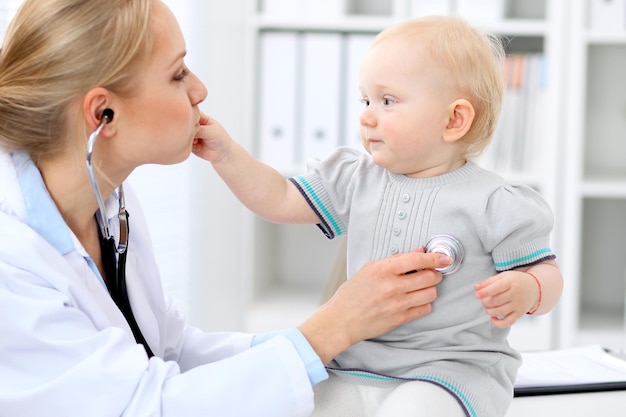 El pediatra está cuidando al bebé en el hospital. La niña está siendo examinada por un médico con estetoscopio. Concepto de atención médica, seguro y ayuda.