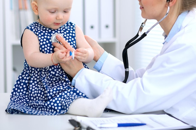 El pediatra está cuidando al bebé en el hospital. La niña está siendo examinada por un médico con estetoscopio. Concepto de atención médica, seguro y ayuda.