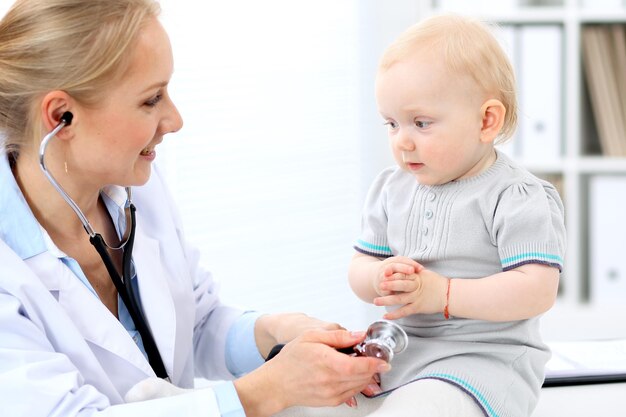 El pediatra está cuidando al bebé en el hospital. La niña está siendo examinada por un médico con estetoscopio. Concepto de atención médica, seguro y ayuda.