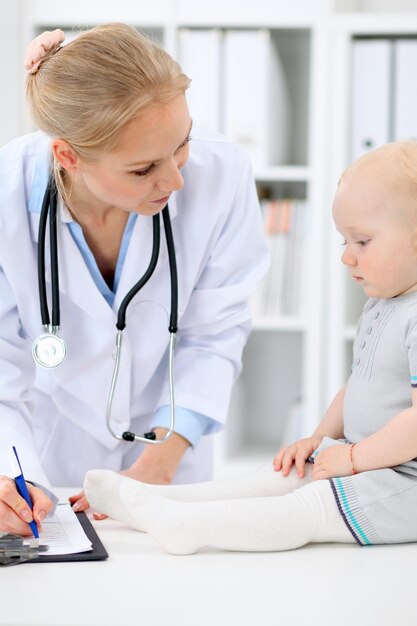 El pediatra está cuidando al bebé en el hospital. La niña está siendo examinada por un médico con estetoscopio. Concepto de atención médica, seguro y ayuda.