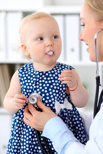 El pediatra está cuidando al bebé en el hospital. La niña está siendo examinada por un médico con estetoscopio. Concepto de atención médica, seguro y ayuda.