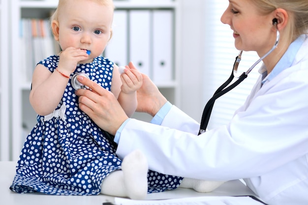 El pediatra está cuidando al bebé en el hospital La niña está siendo examinada por un médico con estetoscopio Concepto de ayuda y seguro de salud