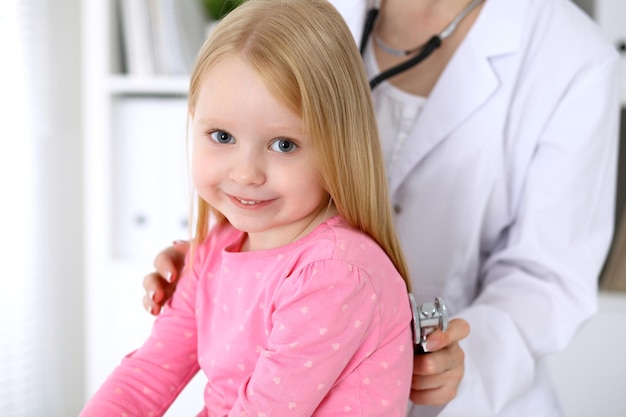 El pediatra está cuidando al bebé en el hospital La niña está siendo examinada por un médico con un estetoscopio Seguro de salud y concepto de ayuda