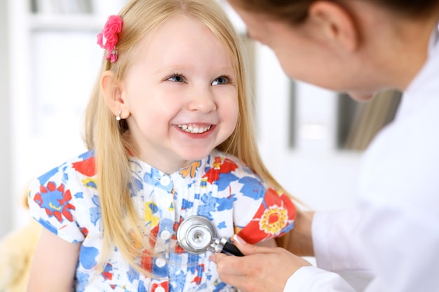 El pediatra está cuidando al bebé en el hospital La niña está siendo examinada por un médico con un estetoscopio Seguro de salud y concepto de ayuda