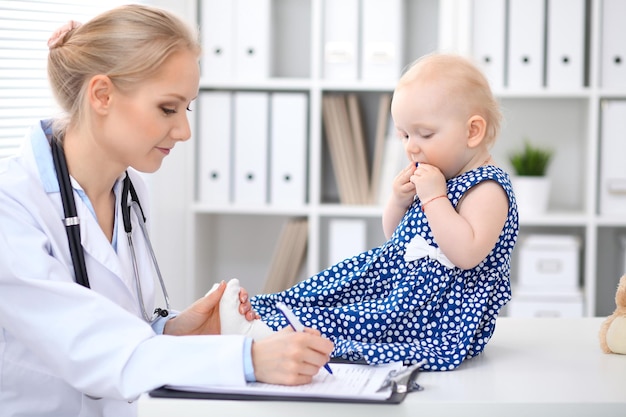 Pediatra está cuidando do bebê no hospital. A menina está sendo examinada pelo doutor com estetoscópio. Cuidados de saúde, seguro e conceito de ajuda.