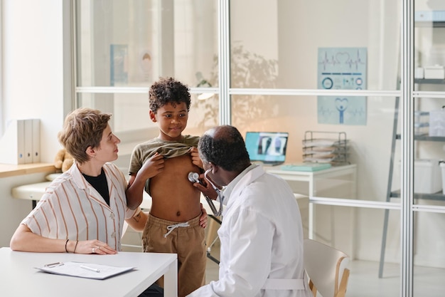 Pediatra examinando menino durante consulta médica