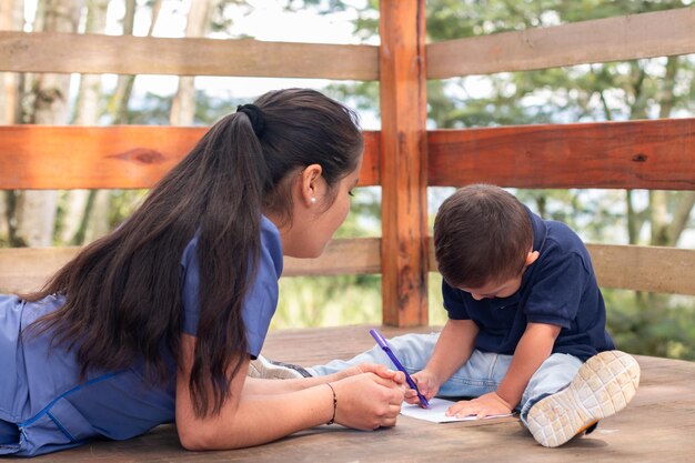 Pediatra latina enseñando a escribir y dibujar a un niño con discapacidad