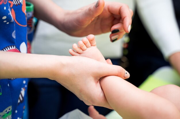 Pediatra manos examinando los pies del pequeño bebé