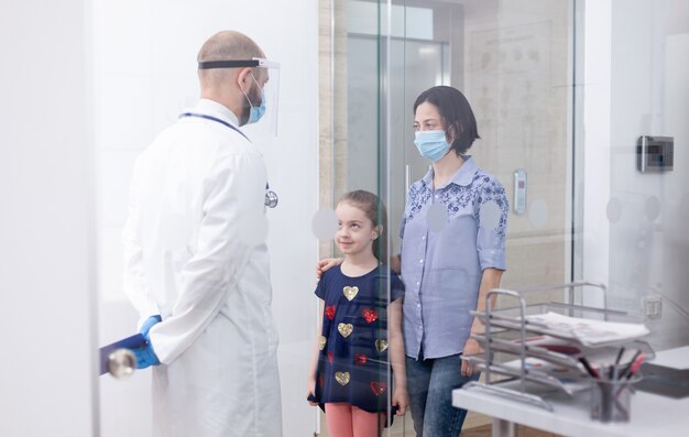 Foto pediatra con mascarilla facial contra coronavirus durante la consulta del niño. médico, especialista en medicina con mascarilla de protección que brinda servicios de salud, consulta.