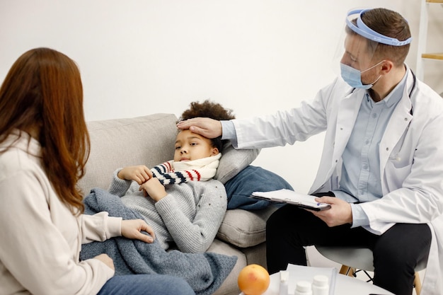 Pediatra masculino segurando a mão na testa de uma menina negra doente