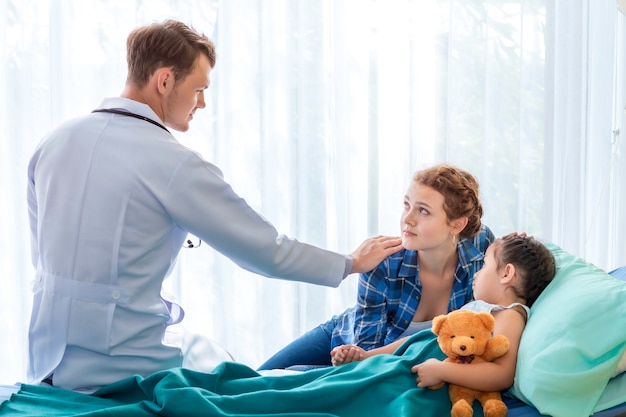 Pediatra (médico) tranquilizar y discutir niña paciente y su madre en el hospital de la habitación.