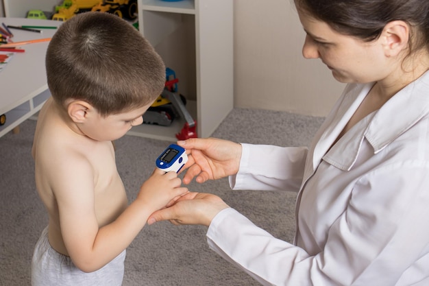 El pediatra mide el nivel de oxígeno en la sangre del niño con un oxímetro de pulso.