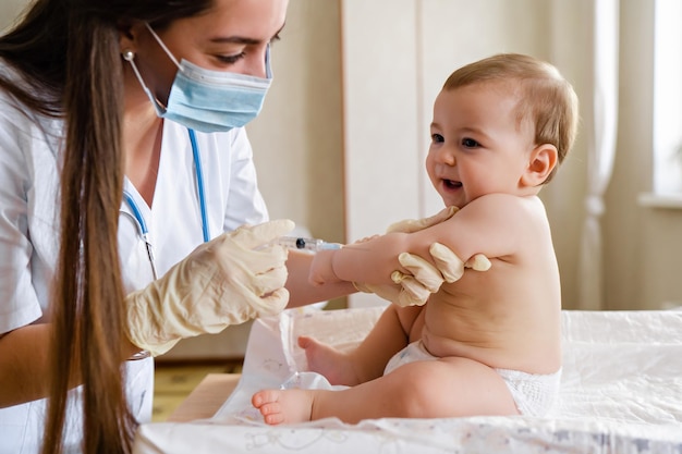 Foto pediatra ou enfermeira dando uma injeção intramuscular de uma vacina à mão do bebê