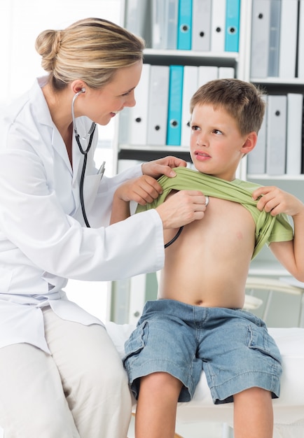 Foto pediatra que examina o menino com estetoscópio