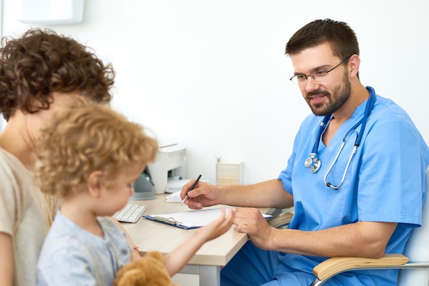 Pediatra trabajando con pequeño paciente en el consultorio