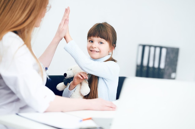 Pediátrica feminina profissional criativa dando a seu pequeno paciente um high five