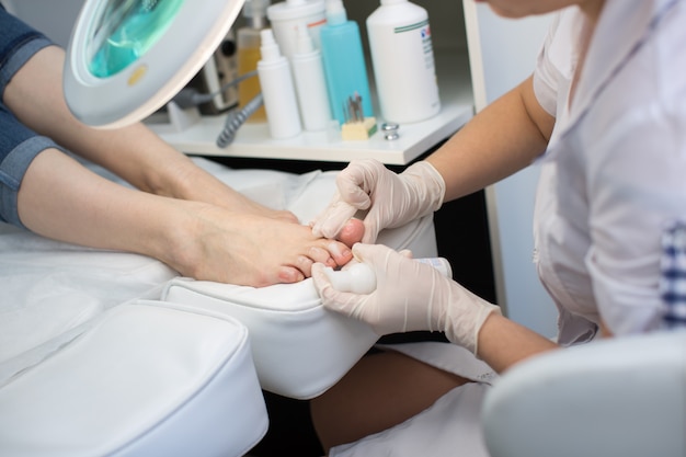 Pedicure removedor de pele morta pé grosa mulher em salão de beleza. Aplicação do creme