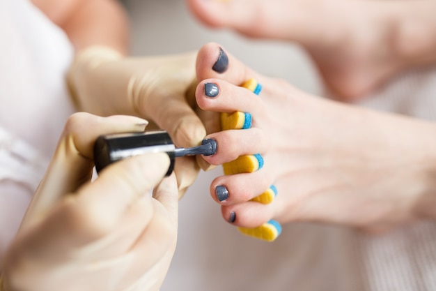 Pedicurista aplicando esmalte de uñas