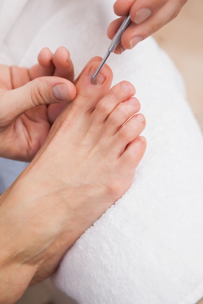 Pedicurista limpiando las uñas de los pies de los clientes