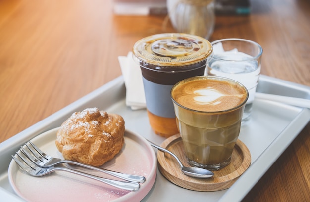 Pedido de café colocado na bandeja sobre a mesa de madeira