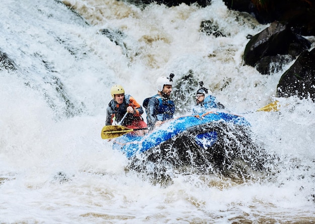 Pedimos una aventura extrema y la conseguimos Foto de un grupo de jóvenes decididos en un bote de goma ocupados remando en fuertes rápidos de río afuera durante el día