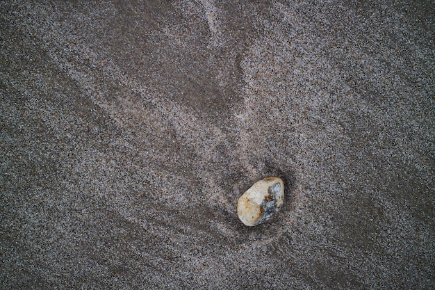 Pedra colorida deitada na areia