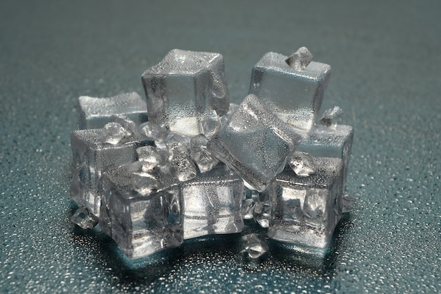 Pedra de gelo na superfície reflexiva do fundo com gotas, ideia de um ambiente frio ou um lugar muito frio