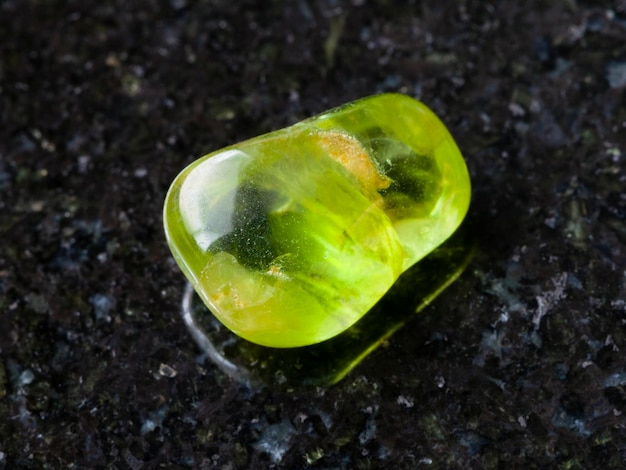 Pedra de gema Peridot lustrada no fundo escuro