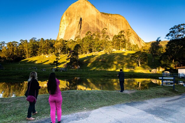 Foto pedra do lagarto in pedra azul domingos martins, bundesstaat espirito santo, brasilien. brasilianischer touristenort. zwei hübsche mädchen fotografieren den blauen felsen