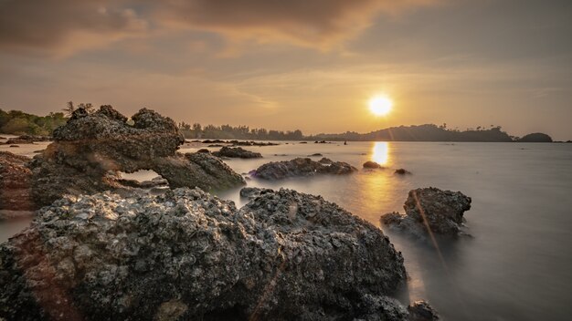 Pedra do mar tropical ao pôr do sol