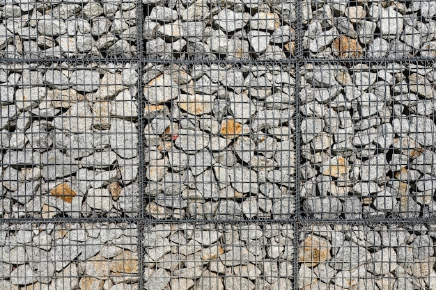 Pedra e seixos na parede de malha de arame.