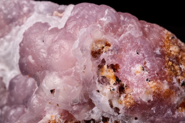 Pedra mineral de Smithsonite rosa macro em microclina em fundo preto