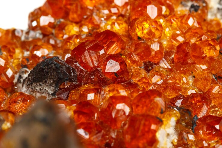 Foto pedra mineral macro spessartine granada vermelha alaranjada com quartzo no fundo branco