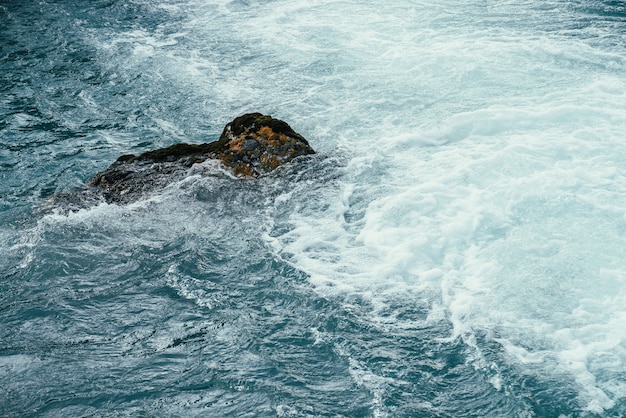Pedra musgosa em água azul de close-up de Rio de montanha.